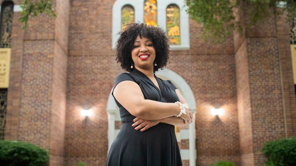 Courtney Bryan standing proudly, wearing a black dress. 