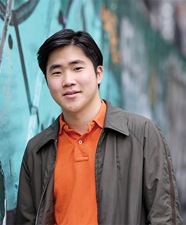 Alumni Maxwell Chung next to wall with mural